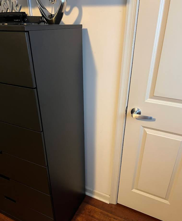Dark modern dresser assembled next to interior door